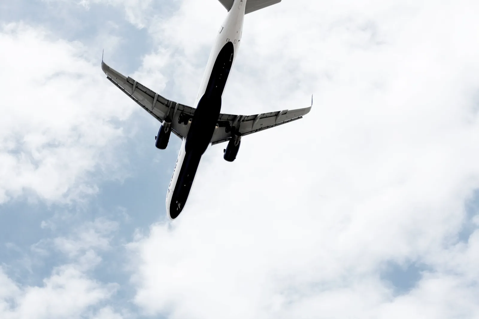 An airliner seen from below as it climbs through white clouds