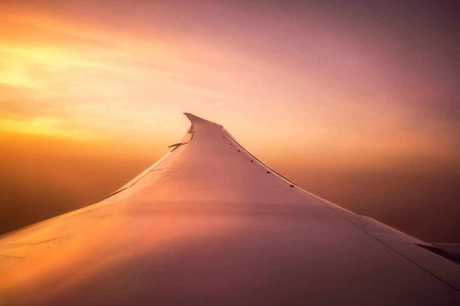 The wing of an aircraft in the glow of a sunset, seen from a window