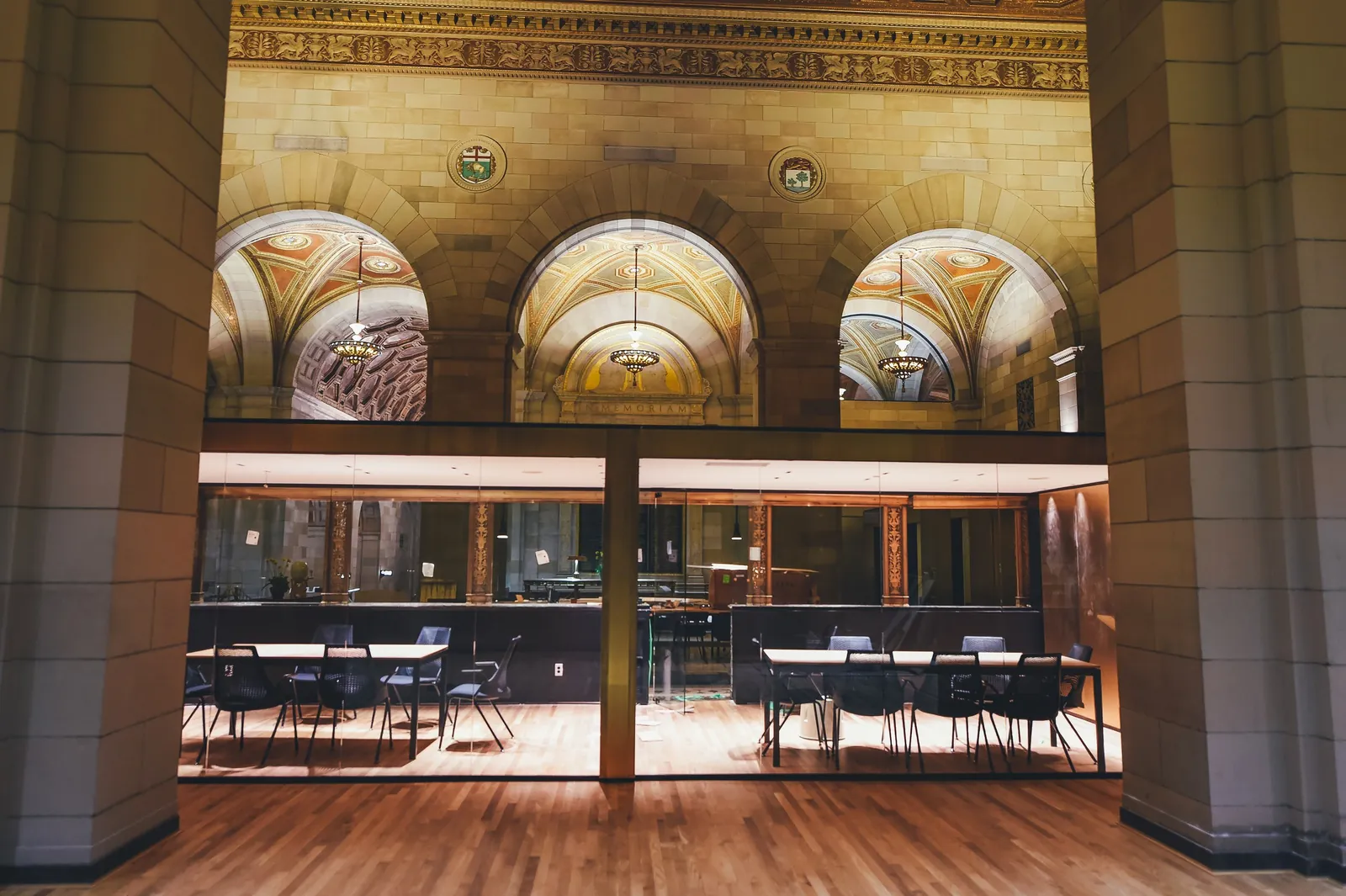 A grand hall with arched windows and tables set out below