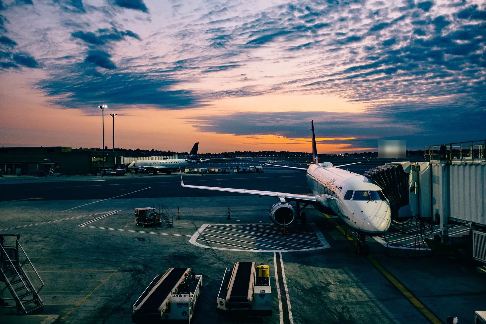 An airliner parked at a gate at dusk under a colourful sky