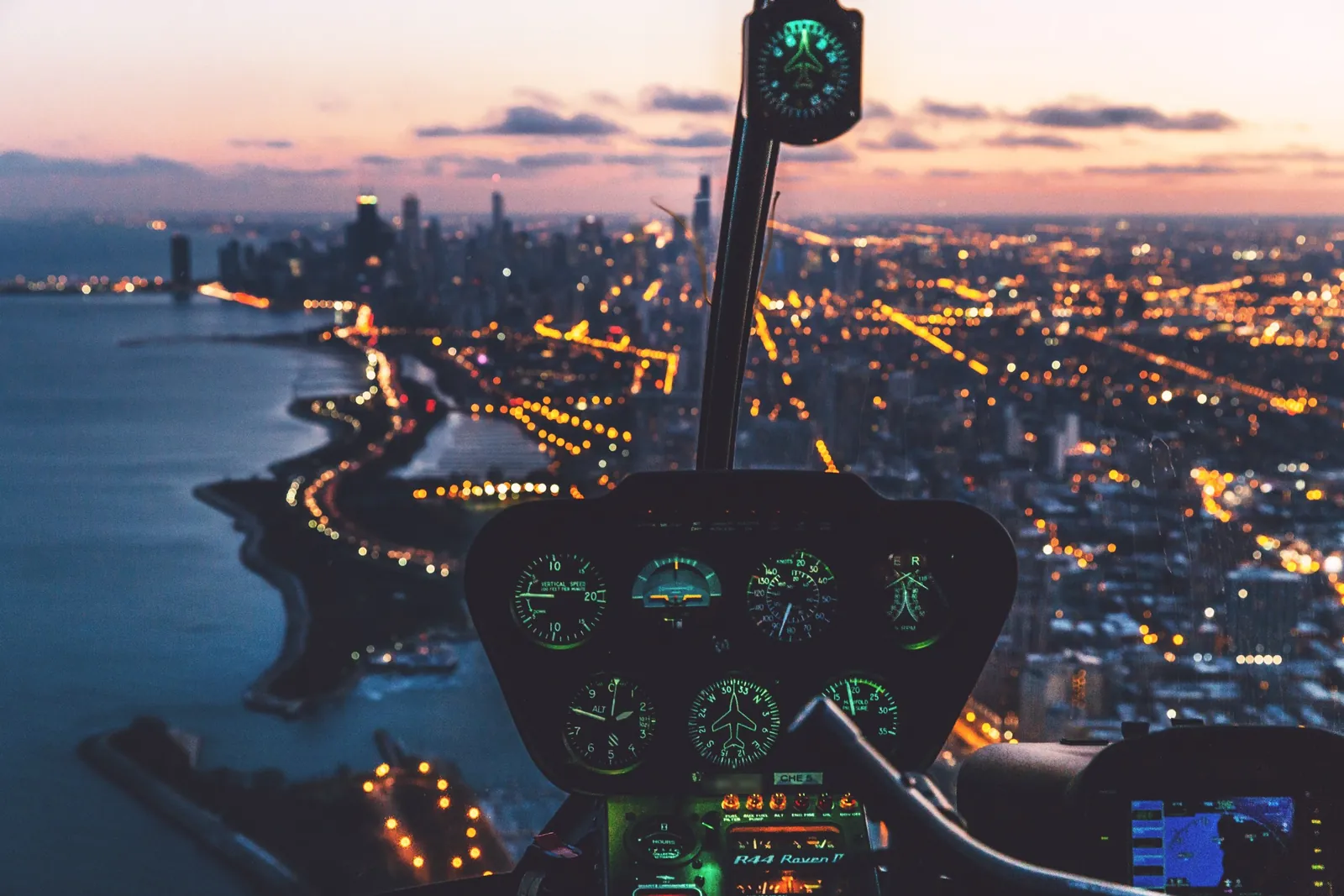 A helicopter cockpit above a city skyline at dusk