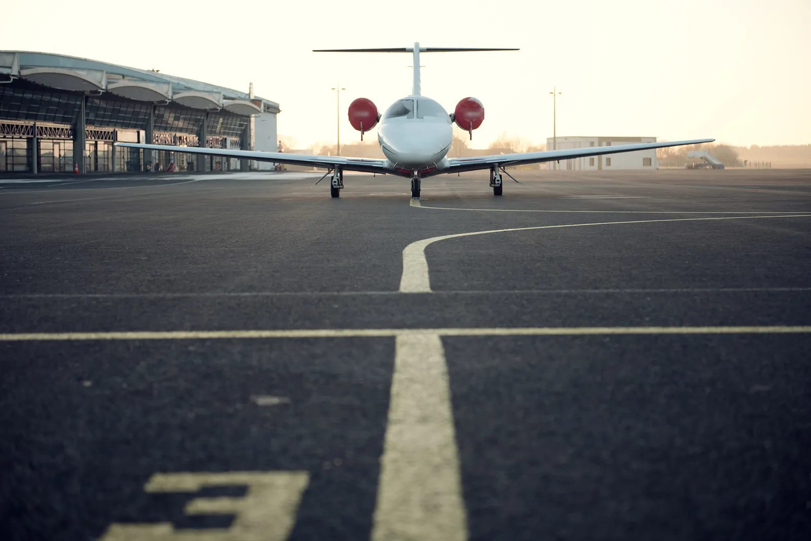 A white business jet seen from the front on an airport apron at sunset
