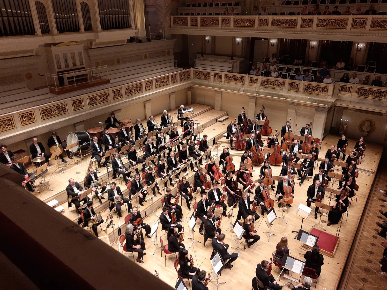 A full orchestra seen from the balcony of a concert hall