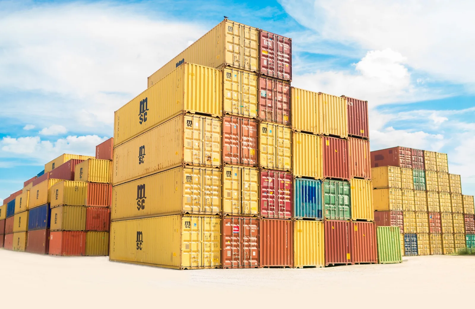 Stacks of yellow and red freight containers under a blue sky