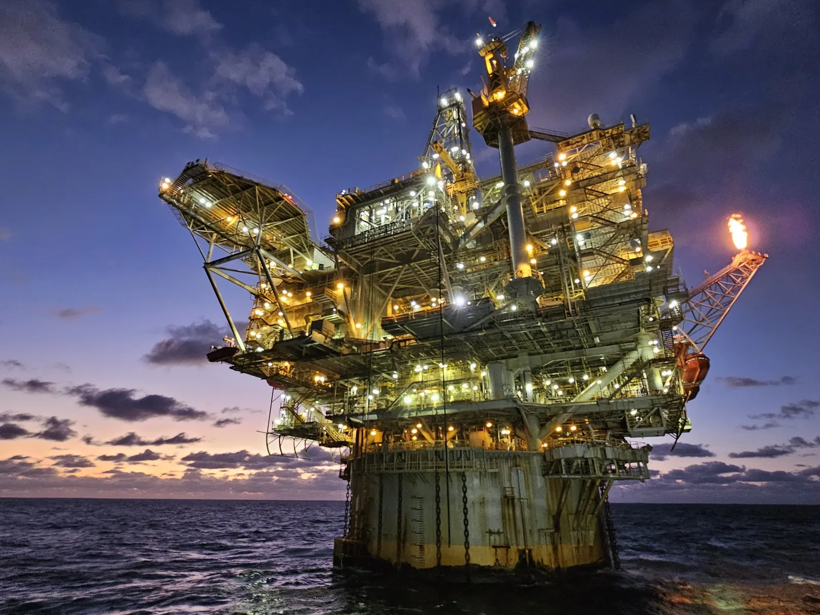 An offshore oil platform lit up at dusk