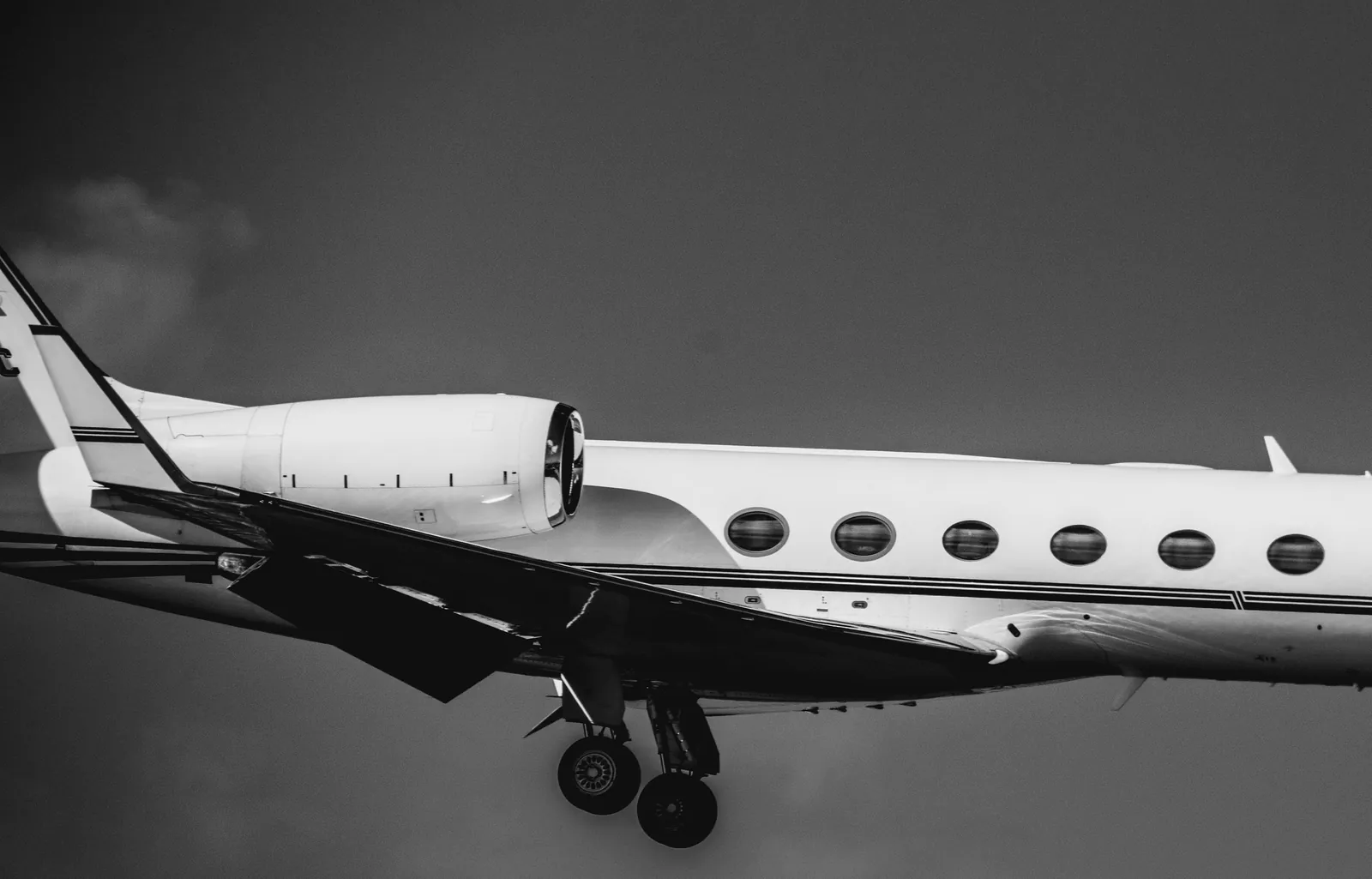 A white private jet on approach to land, in black and white